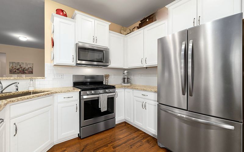 White kitchen with a stainless French door refrigerator, gas range and over-the-range microwave