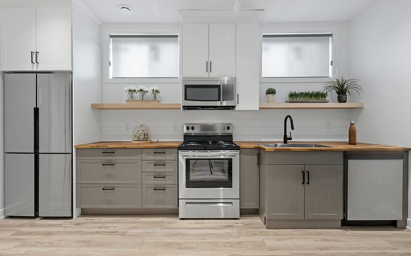 Kitchen with gray lower cabinets and butcher-block counters, a stainless refrigerator, electric range, microwave and dishwasher