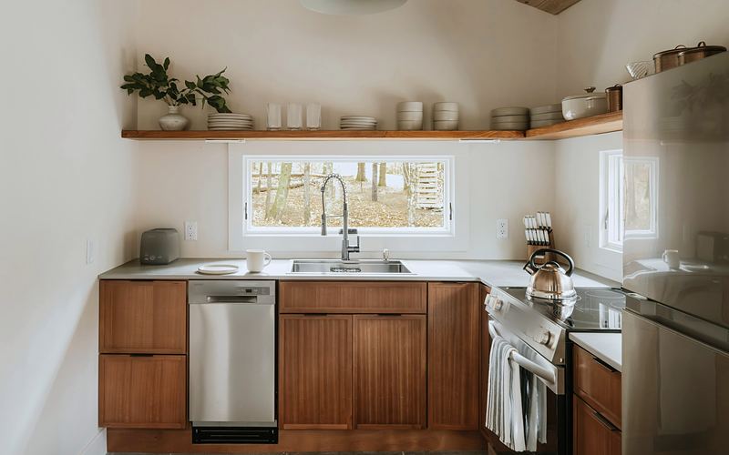 Small kitchen with wood cabinets, a window over the sink, open shelves, a stainless dishwasher, range and refrigerator