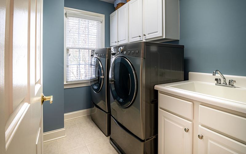 Laundry room with blue walls, a front-load washer and dryer on pedestals, and a utility sink