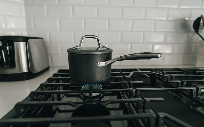 Saucepan on a gas cooktop burner with a blue flame