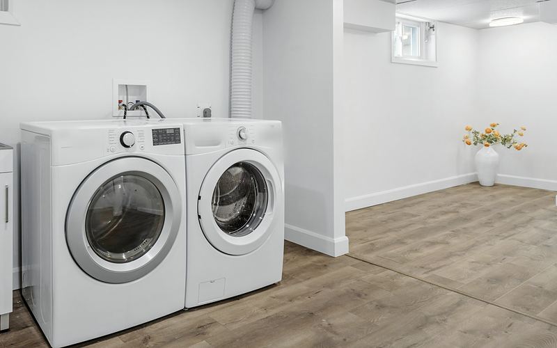 White front-load washer and dryer side by side in a basement laundry area