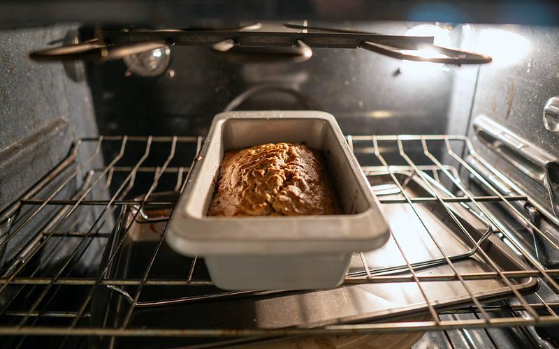 Loaf of bread baking on the rack inside a lit oven