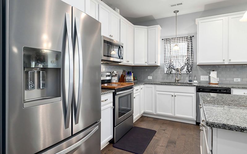 Stainless French door refrigerator with a water and ice dispenser in a white kitchen