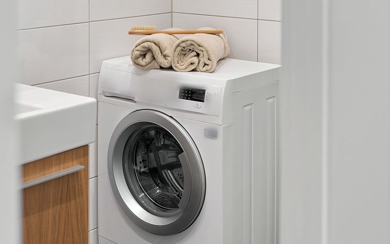 White front-load washing machine with rolled towels on top